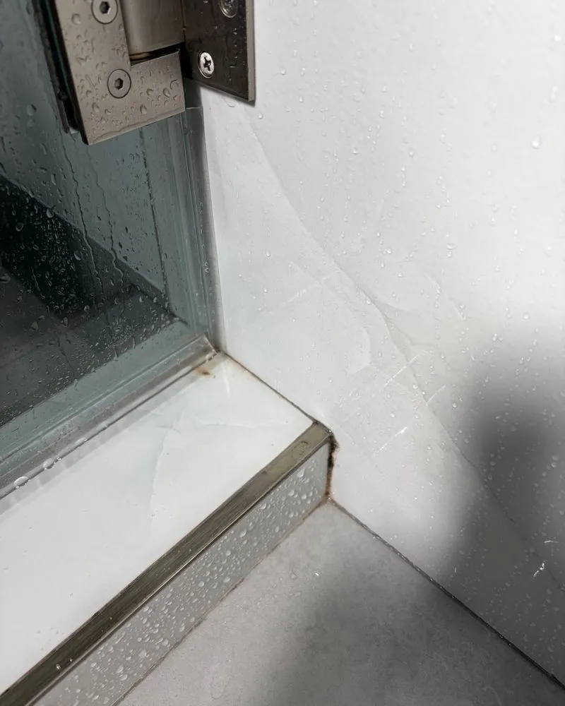 Shower threshold corner with water spots and grime before cleaning