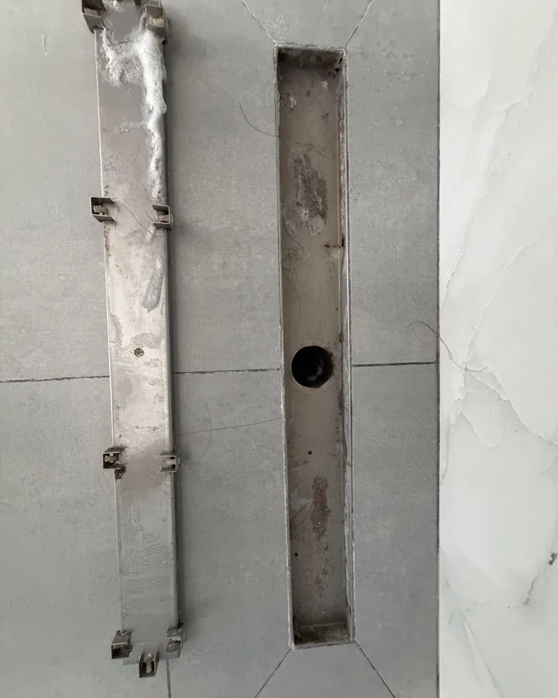 Shower drain channel and grate with built-up grime before cleaning