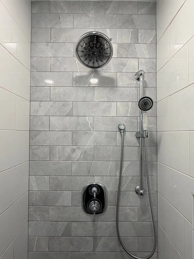 Clean grey tiled shower wall with chrome fixtures